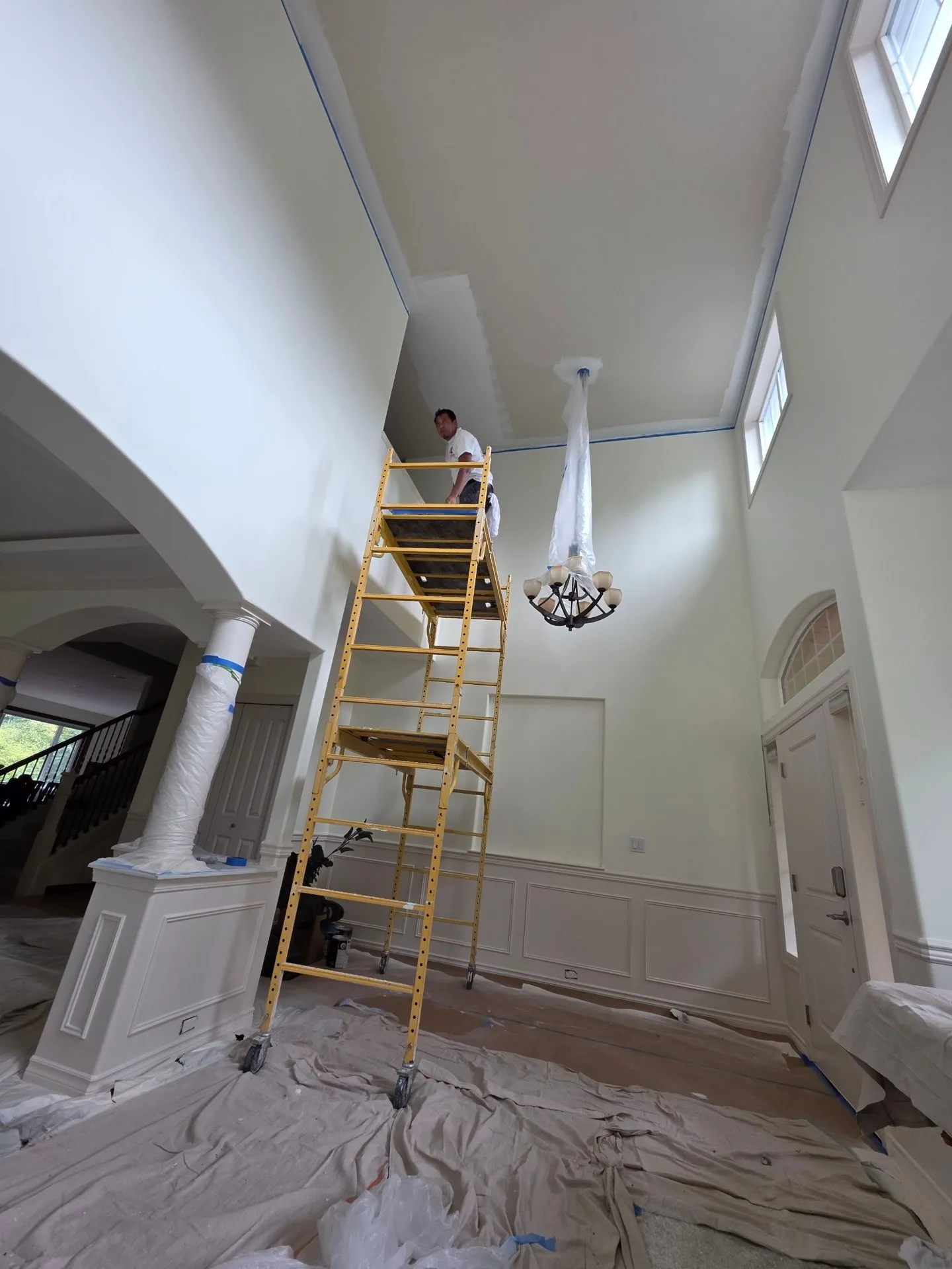 Interior foyer with high-ceiling painting in progress