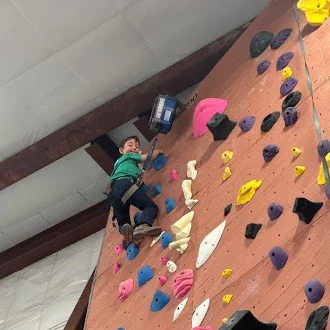 Young climber reaching for a hold on the climbing wall at the Bothell UW campus